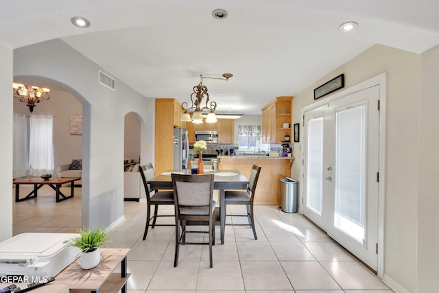 dining area with french doors, light tile patterned floors, and an inviting chandelier