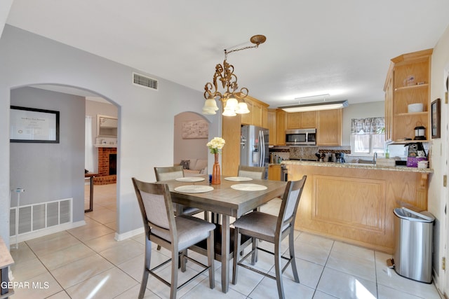 dining space with a fireplace, a chandelier, and light tile patterned flooring