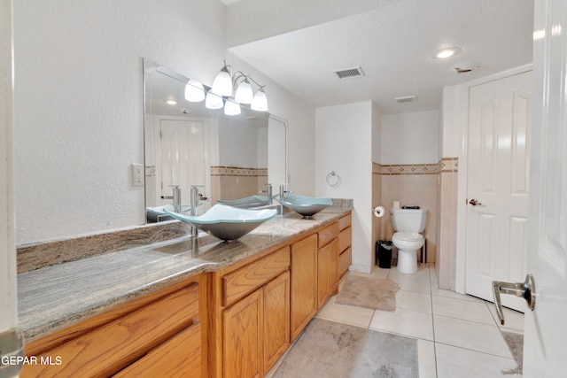 bathroom with tile patterned flooring, a textured ceiling, vanity, and toilet