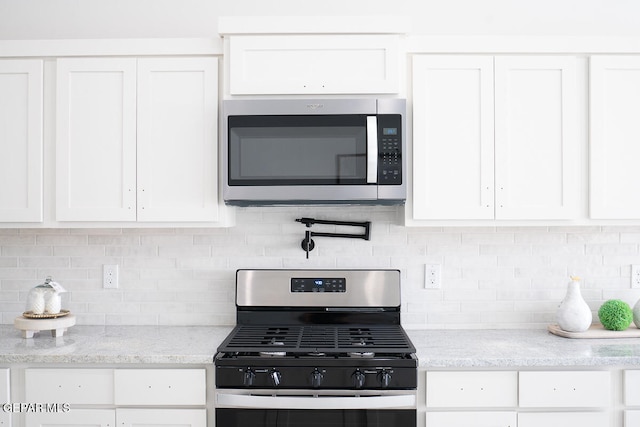 kitchen featuring white cabinets, stainless steel appliances, and backsplash