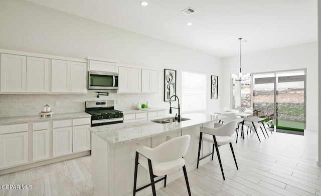 kitchen featuring white cabinetry, appliances with stainless steel finishes, sink, and a center island with sink