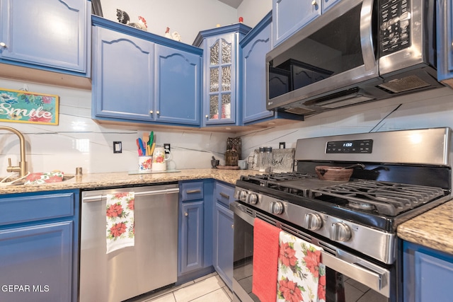 kitchen featuring decorative backsplash, light stone countertops, blue cabinets, and stainless steel appliances