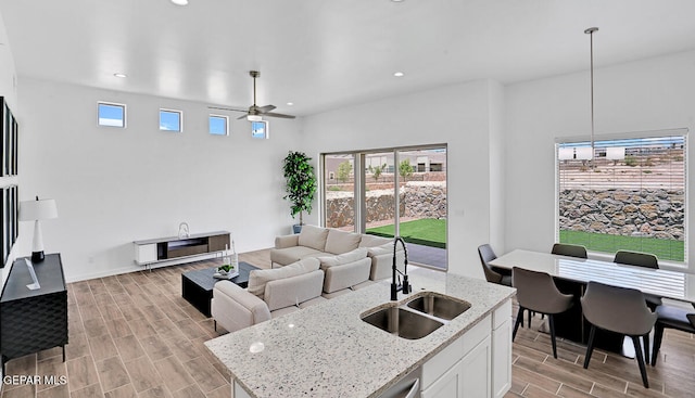 kitchen with ceiling fan, sink, light hardwood / wood-style flooring, white cabinets, and hanging light fixtures