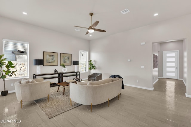 living room featuring ceiling fan, plenty of natural light, and light hardwood / wood-style floors