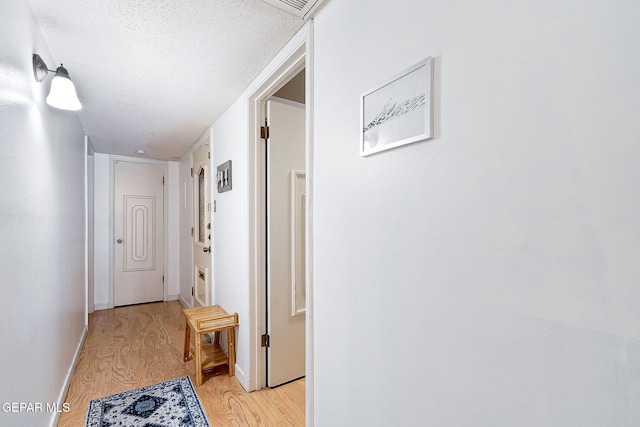 corridor featuring light hardwood / wood-style floors and a textured ceiling