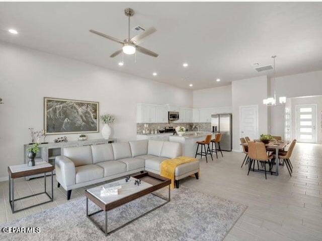 living room featuring ceiling fan with notable chandelier and light hardwood / wood-style floors