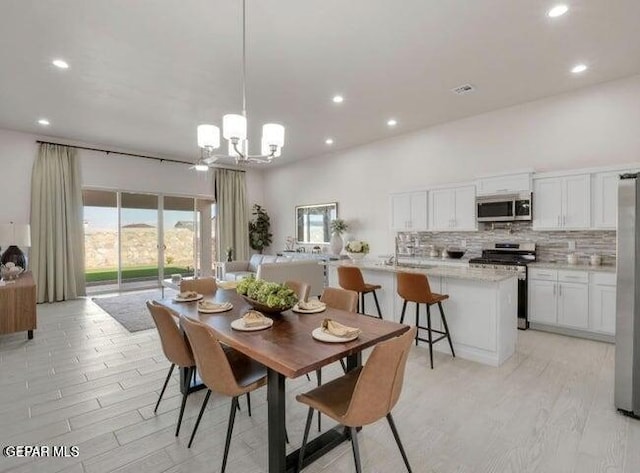 dining area with light hardwood / wood-style flooring and an inviting chandelier