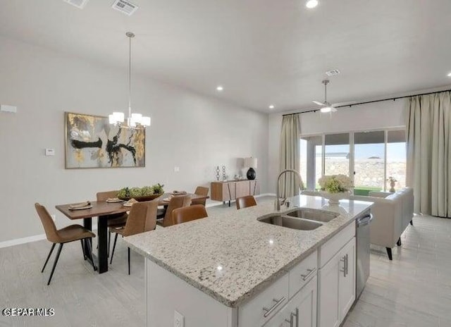 kitchen with sink, hanging light fixtures, stainless steel dishwasher, an island with sink, and white cabinets