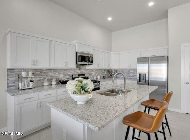 kitchen with a center island with sink, white cabinetry, sink, and appliances with stainless steel finishes