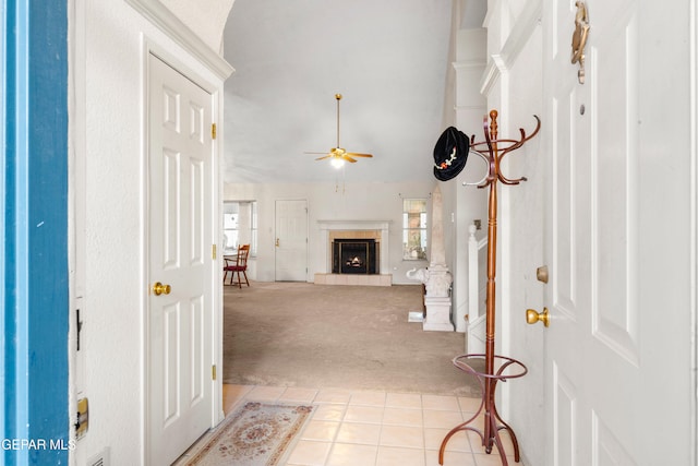 carpeted foyer with ceiling fan and a tile fireplace