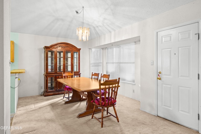 carpeted dining room with a notable chandelier and a textured ceiling