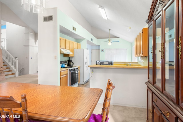 kitchen featuring light carpet, vaulted ceiling, ceiling fan, gas range oven, and kitchen peninsula