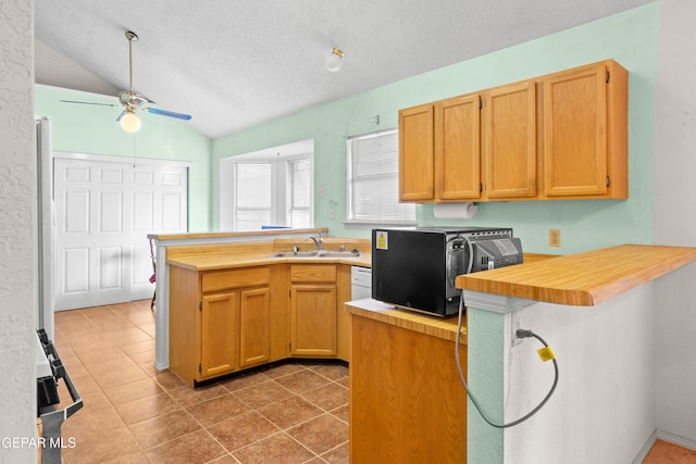 kitchen with wooden counters, sink, vaulted ceiling, ceiling fan, and kitchen peninsula