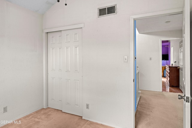 hallway featuring a textured ceiling, lofted ceiling, and light carpet