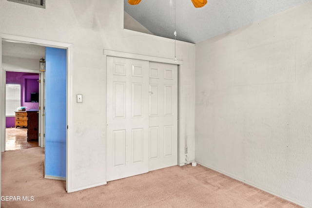 unfurnished bedroom featuring carpet, ceiling fan, a closet, and vaulted ceiling