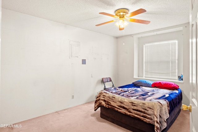 bedroom featuring a textured ceiling, light colored carpet, and ceiling fan