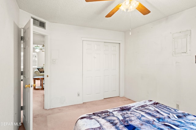 carpeted bedroom featuring ceiling fan, a textured ceiling, electric panel, and a closet