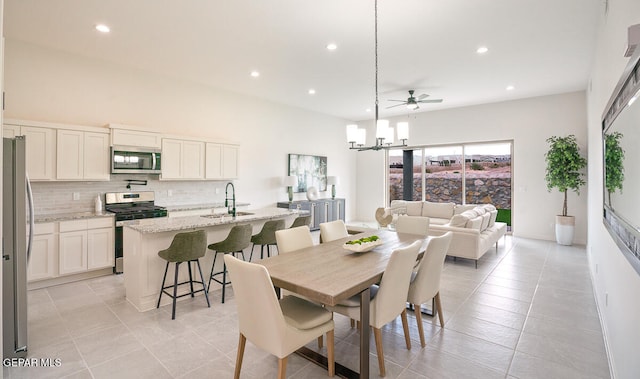 tiled dining space featuring ceiling fan with notable chandelier and sink