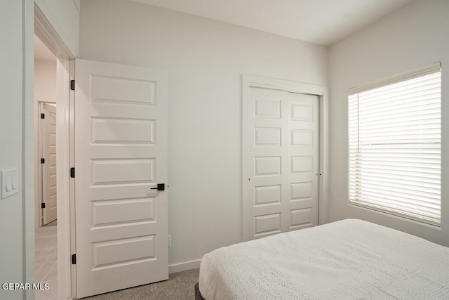 carpeted bedroom featuring multiple windows and a closet