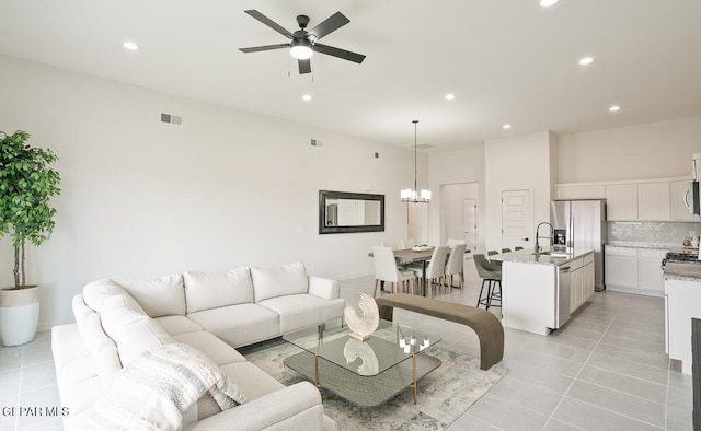 living room with sink, ceiling fan with notable chandelier, and light tile patterned floors