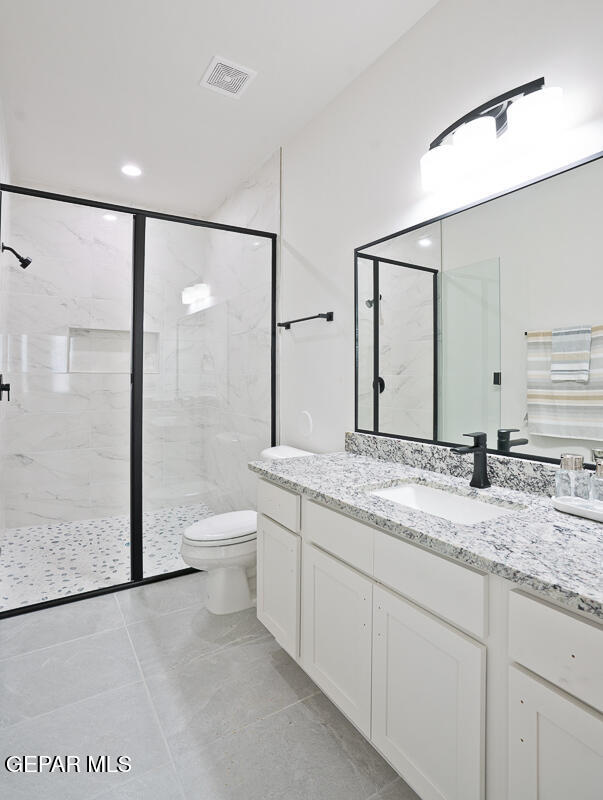 bathroom with a shower with door, vanity, and toilet