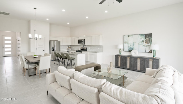 tiled living room featuring sink and ceiling fan with notable chandelier