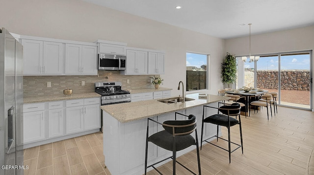 kitchen with white cabinets, stainless steel appliances, hanging light fixtures, and sink