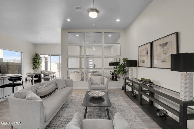 living room featuring ceiling fan with notable chandelier and hardwood / wood-style floors