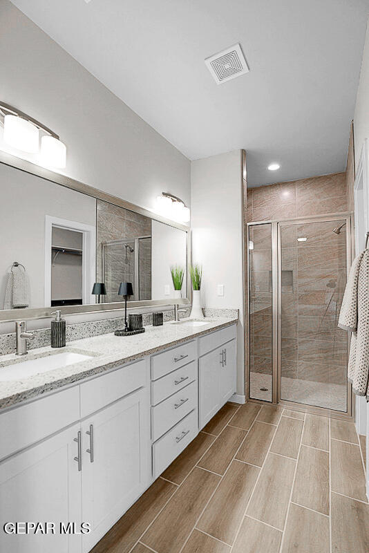 bathroom with a shower with door and vanity