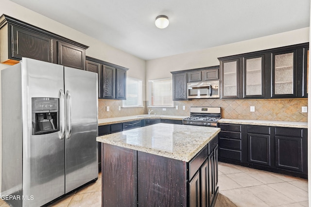 kitchen featuring decorative backsplash, glass insert cabinets, a center island, stainless steel appliances, and dark brown cabinets