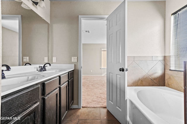 full bathroom featuring a bath, double vanity, visible vents, and a sink