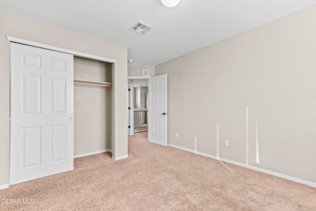 unfurnished bedroom featuring light carpet, a closet, visible vents, and baseboards