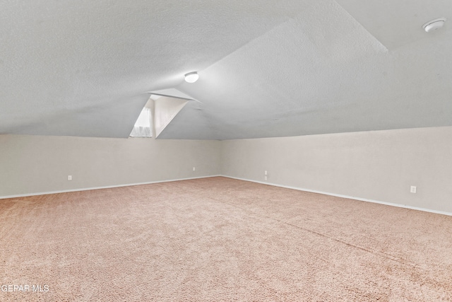 bonus room featuring a textured ceiling, baseboards, carpet flooring, and lofted ceiling