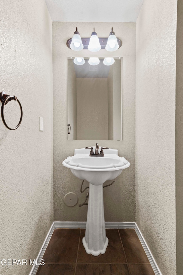 bathroom featuring a textured wall, baseboards, and tile patterned floors