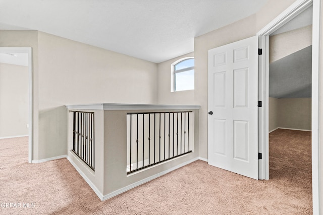 corridor featuring light carpet and baseboards