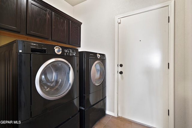 laundry area with light tile patterned floors, washing machine and clothes dryer, and cabinet space