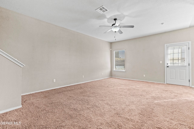 carpeted empty room with visible vents, plenty of natural light, a ceiling fan, and baseboards