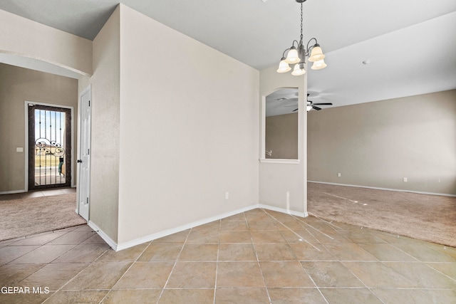 spare room featuring light colored carpet, light tile patterned flooring, baseboards, and ceiling fan with notable chandelier