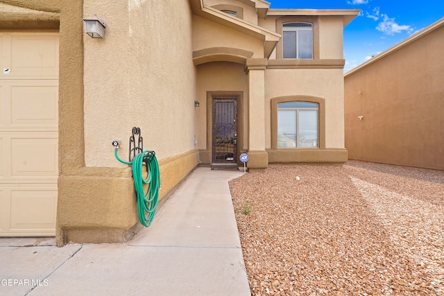 property entrance with an attached garage and stucco siding