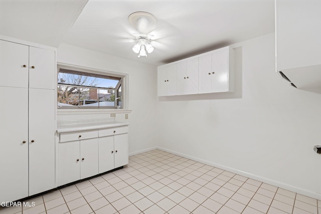 interior space with white cabinetry, ceiling fan, and light tile patterned flooring