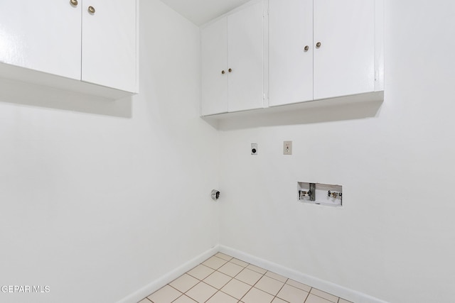 laundry area featuring electric dryer hookup, hookup for a washing machine, light tile patterned flooring, and cabinets