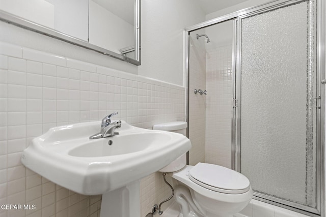 bathroom featuring a shower with door, tile patterned flooring, tile walls, and toilet