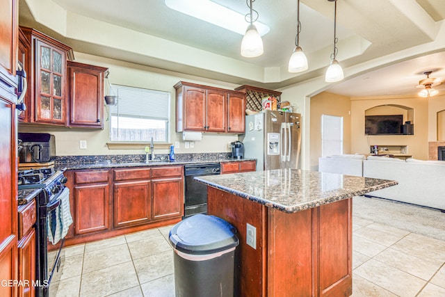 kitchen with sink, decorative light fixtures, a tray ceiling, a kitchen island, and black appliances