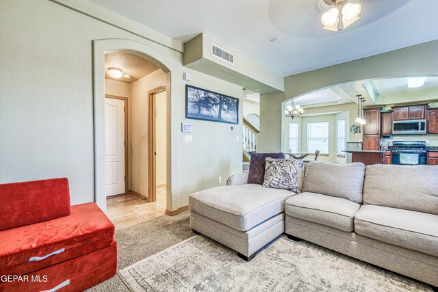 tiled living room featuring ceiling fan with notable chandelier