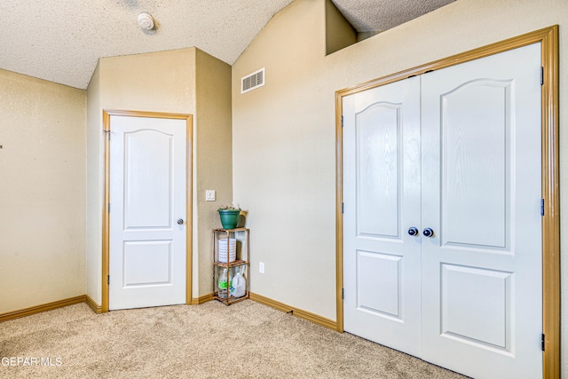 unfurnished bedroom with a textured ceiling, lofted ceiling, light carpet, and a closet