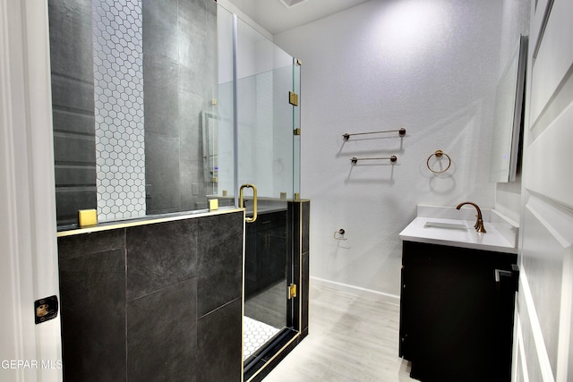 bathroom with hardwood / wood-style flooring, vanity, and walk in shower