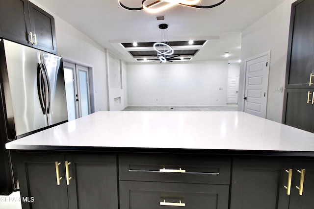 kitchen with gray cabinetry, a chandelier, a center island, stainless steel refrigerator, and hanging light fixtures