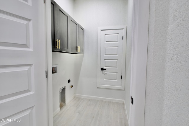 clothes washing area featuring cabinets, gas dryer hookup, washer hookup, and light hardwood / wood-style floors