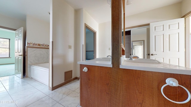 bathroom with a bathing tub, vanity, and tile patterned floors