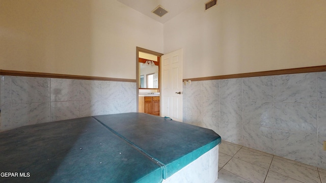 bathroom with sink, high vaulted ceiling, and tile walls